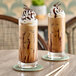 Two glasses of mocha java coffee with whipped cream and chocolate drizzle on a table.
