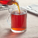 A person using a teapot to pour Davidson's Organic Earl Grey tea into a glass cup.