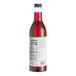 A close-up of a bottle of Capora strawberry flavoring syrup with red liquid inside.