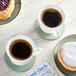 A table with several cups of Lavazza Italian Roast coffee and a donut on a plate.