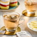 A glass cup of Tazo chamomile tea with a bag in it on a plate.