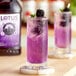 A glass of purple Lotus Plant Power energy drink with blackberries and mint.