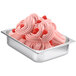 A metal container of Fabbri raspberry flavoring paste on a counter next to a bowl of pink ice cream.