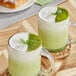 Two glasses of green Fanale matcha drinks with a sprig of mint on top.