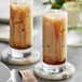 Two glasses of iced coffee on a table with coasters and a bottle of Fanale Brown Sugar Syrup.