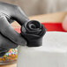 A hand holding a black rose made of Satin Ice black gum paste on a white cake.