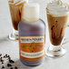 A bottle of Nielsen-Massey Pure Chocolate Extract next to a glass of chocolate liquid.