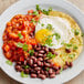 A plate of food with beans, tortillas, and a fried egg seasoned with Goya Adobo.