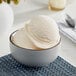 A bowl of I. Rice peach hard serve ice cream with a scoop of ice cream.