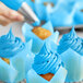 A close up of a cupcake with a blue swirl of frosting on top.