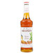 A bottle of Monin butter pecan flavoring syrup with a white label.