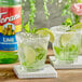 Two glasses of limeade with lime slices and a bottle of Torani Lime Flavoring Syrup.