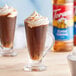 A glass of coffee with whipped cream and Torani Classic Caramel Flavoring syrup.