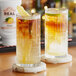 Two glasses of ginger-infused syrup on a table in a cocktail bar.