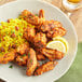 A plate of chicken wings seasoned with Regal Cajun Wing Rub served with rice and a lemon wedge.