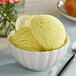 A bowl of yellow ice cream with lemon slices on top.