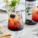 A glass of red liquid with ice and Monin Premium Blackberry Flavoring syrup with a blackberry garnish.