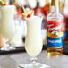 A glass of white liquid flavored with Torani Pineapple Syrup on a napkin with a cherry on top.
