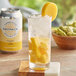 A glass of DayPack Mango Non-Alcoholic Sparkling Hop Water with ice and a slice of mango on top.