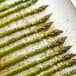 Asparagus spears arranged on a baking sheet.