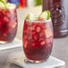 A glass of red Finest Call Sangria with a lime slice on the rim.