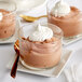 A group of glass cups with chocolate desserts on top.