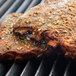 Regal Big Flavor BBQ Rub seasoning being used on ribs cooking on a grill.