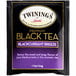 A white and purple Twinings Blackcurrant Breeze Tea packet with black tea bags inside.