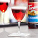 A red wine glass filled with Torani blackberry flavored liquid with a blackberry garnish.