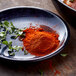 A plate with a pile of red powder and green leaves.