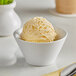 A bowl of Oringer peach ice cream on a table with a spoon on a cloth.