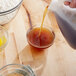 A person pouring brown liquid from a pitcher into a bowl of brown liquid.