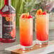 Two glasses of orange and red Regal Cocktail Grenadine with cherries and orange slices on a table in a cocktail bar.