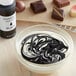 A bowl of white liquid with black swirls using Chefmaster Black Oil-Based Candy Color.