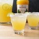 A glass of Monin margarita with a lime slice on the rim.