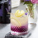 A glass of lavender drink with a lemon slice on the rim.