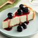 A slice of cheesecake with Luxardo Maraschino Cherries and berries on top.