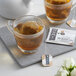 A glass cup of Numi Organic Dry Desert Lime tea with a tea bag and a teapot.
