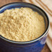 A blue bowl filled with Regal Ground Hot English Mustard Seed on a table.