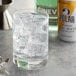 A glass of water with ice and a can of Polar tonic water on a table.