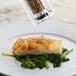A plate of food with a pepper shaker filled with Regal Whole White Peppercorn.