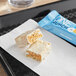 A white and orange ONE Crunch Marshmallow Treat protein bar on a napkin next to a packet.