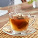 A glass cup of Bigelow Cinnamon and Blackberry herbal tea with steam and a tea bag.
