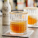 A couple of glasses with brown liquid on a table.