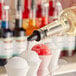 A person pouring Hawaiian Shaved Ice Coconut Snow Cone Syrup over snow cones.