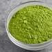 A bowl of Tenzo Organic Ceremonial Matcha green powder on a table.