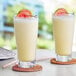 Two glasses of Capora Guava Passion Fruit smoothies with fruit on top.