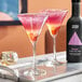 Two martini glasses filled with pink and orange Three Spirit Livener on a tray.