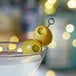 A martini glass with green olives in it on a table.