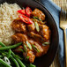 A bowl of curry with rice and green beans.